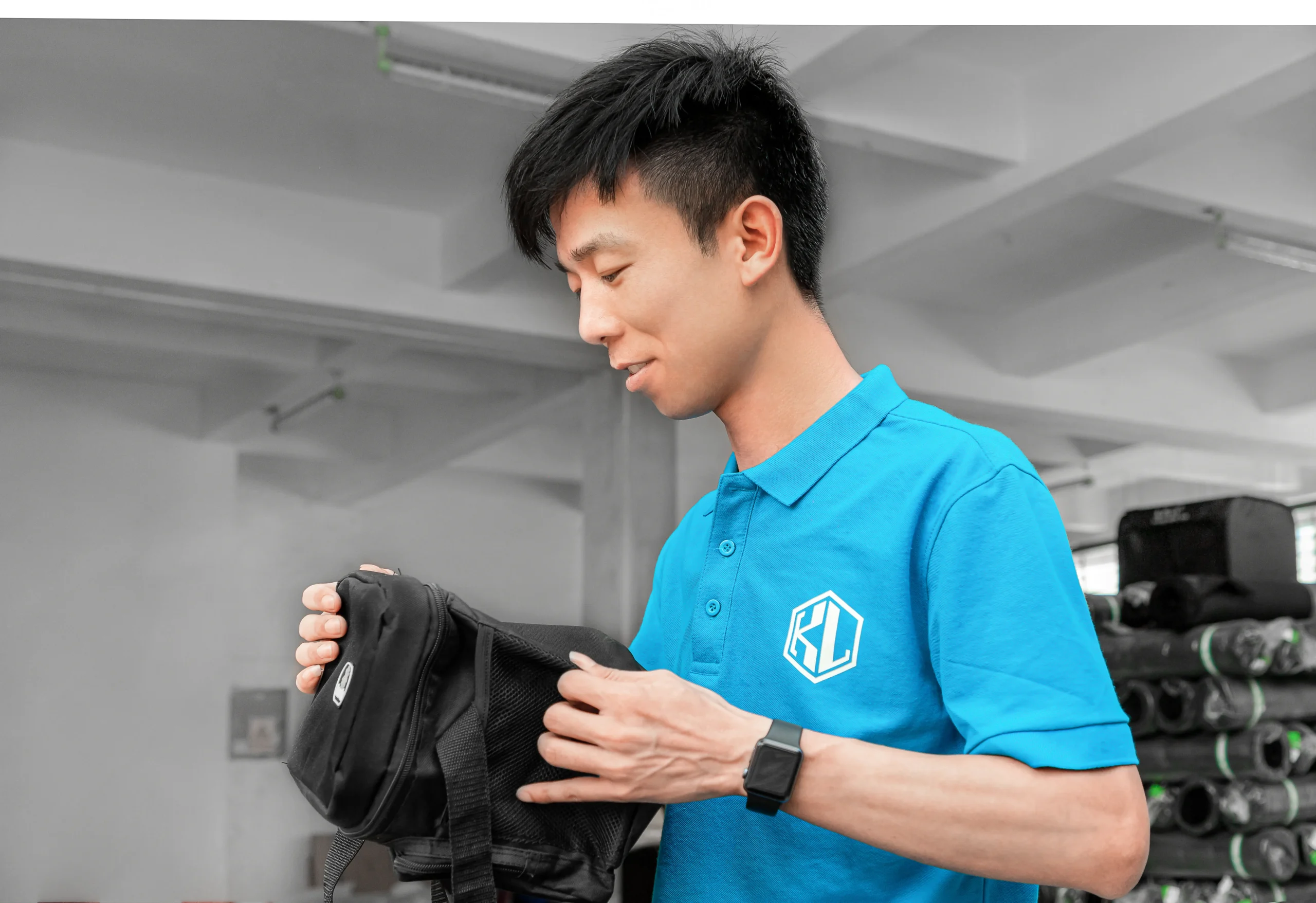 Male employee inspecting a small black Custom Backpack. Professional Supplier for Private Label backpacks.