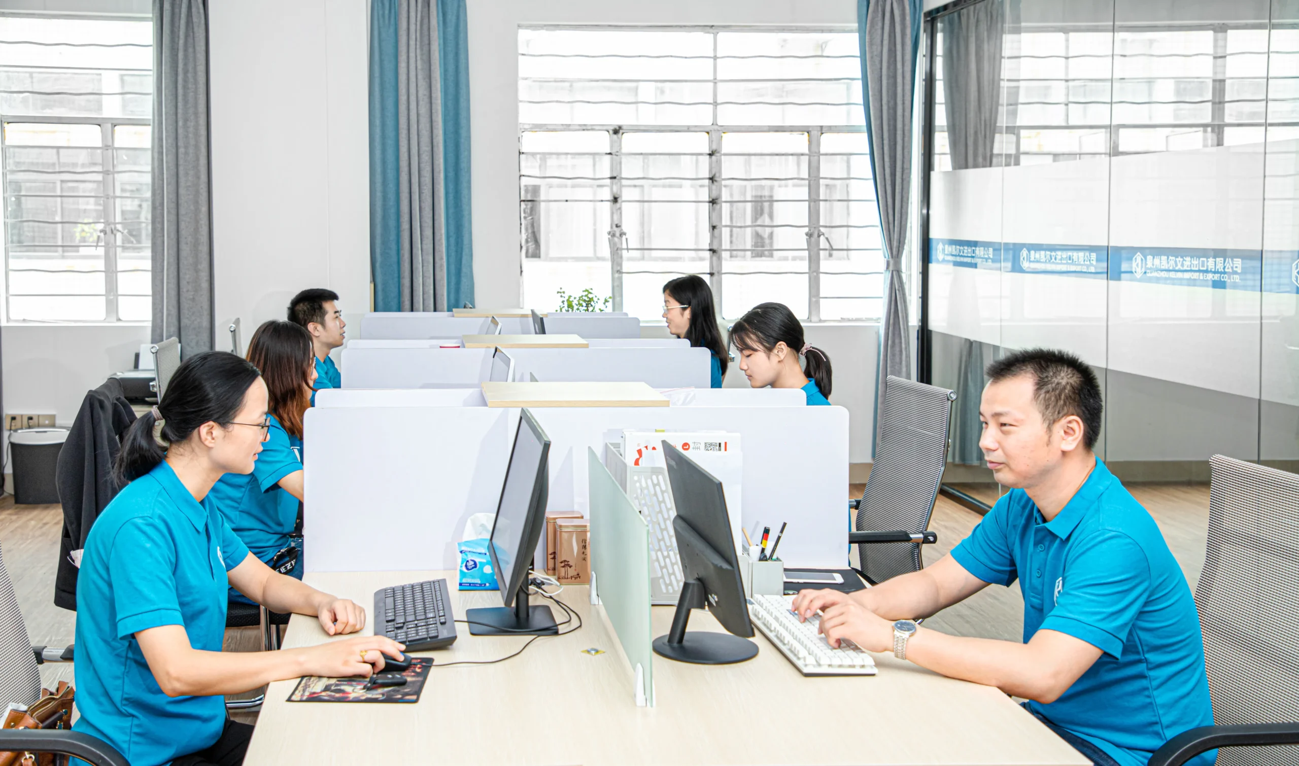 Team of office workers sitting at computers. Professional back-end operation and client service at a Backpack Manufacturer.