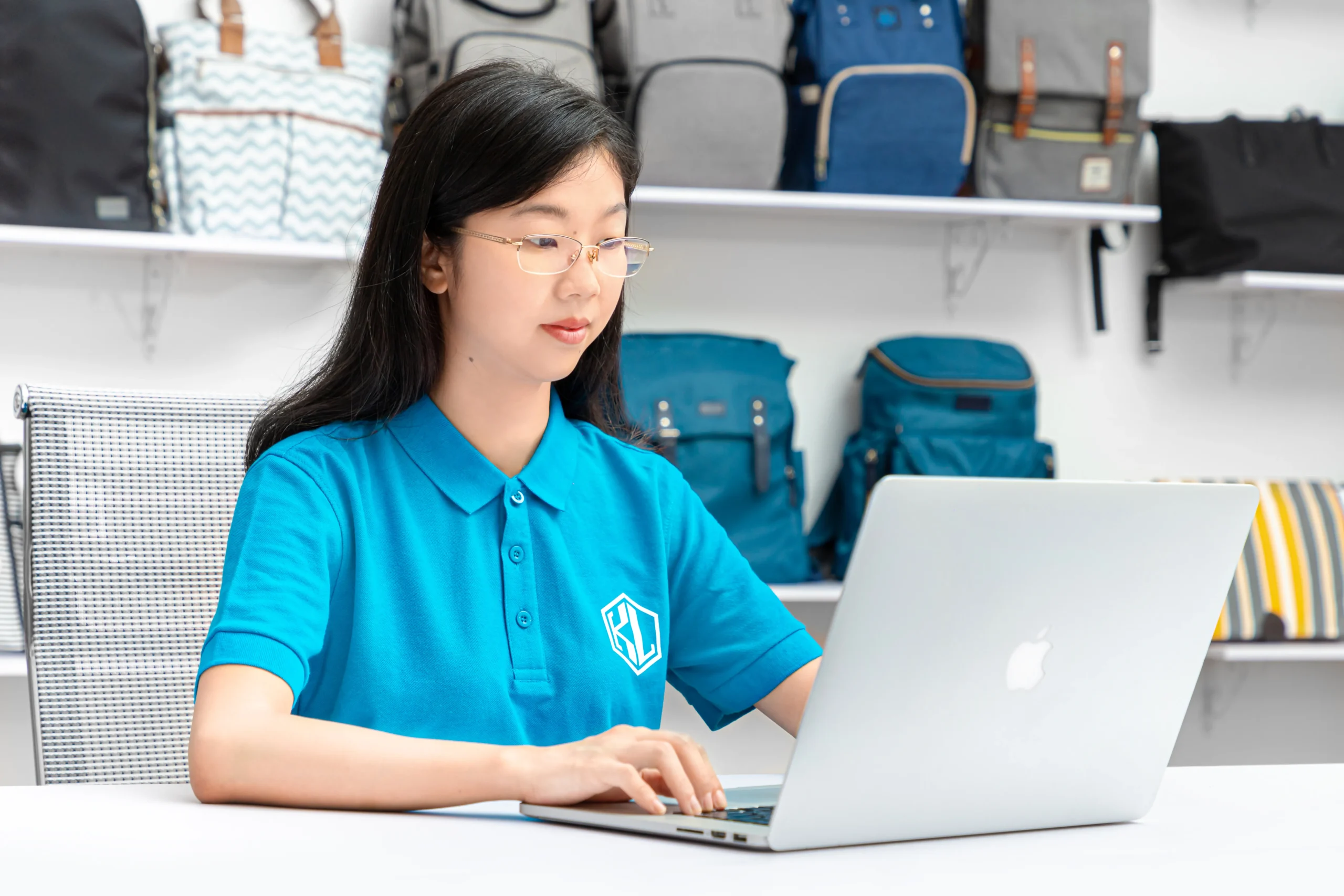 Female professional working on a laptop in a backpack showroom. Customer service at a leading Backpack Supplier.