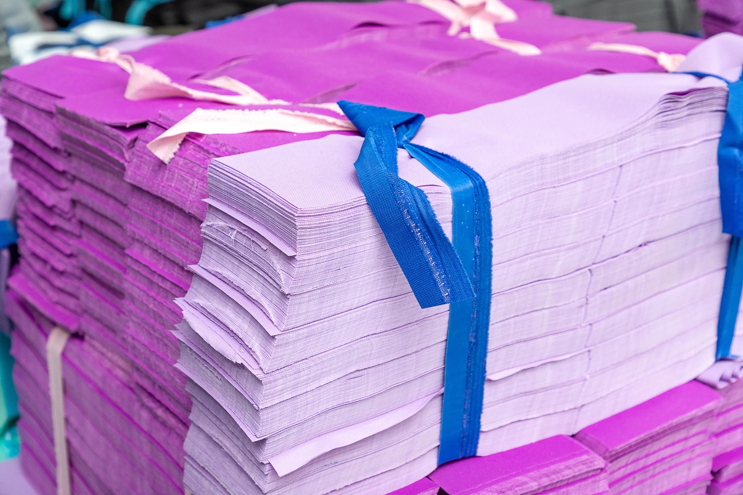 Stacks of neatly bound purple fabric cutouts. Pre-production material sorting at a Backpack Manufacturer.