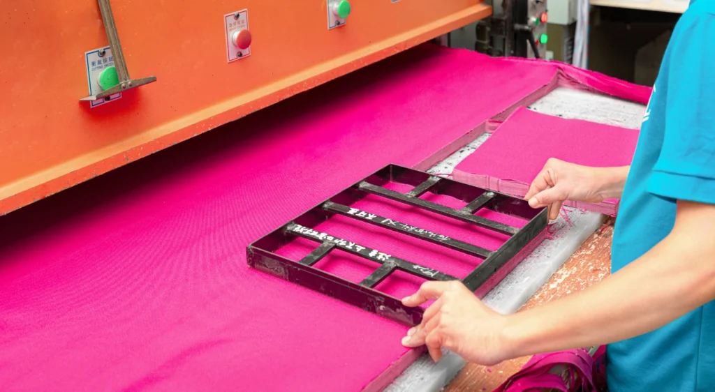 Operator using a template on a cutting machine to cut pink fabric. Industrial cutting process at an OEM Manufacturer.