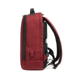 Side profile of a minimalist burgundy backpack showing its slim profile, luggage strap, and side charging port. Travel-friendly bag by a Backpack OEM Supplier.