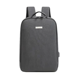 Front view of a minimalist dark grey backpack with a rectangular silver logo plate and top grab handle. Professional business bag by a Backpack Manufacturer.