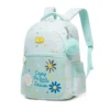 Slanted front view of a mint green daisy backpack featuring a yellow logo patch, embroidered daisies, a blue pom-pom, and floral zipper pulls. Cute school bag by a Backpack Supplier.