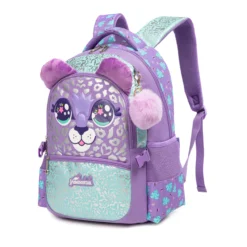 Slanted front view of a cute kids' backpack featuring 3D plush ears, large sparkling eyes, and a purple fur pom-pom charm. Adorable school bag by a Backpack Manufacturer.