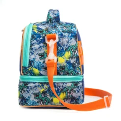 Side view of a blue dinosaur lunch bag showing the deep bottom compartment, white strap swivel clip, and vibrant dinosaur graffiti pattern. Functional luxury cooler by a Backpack Manufacturer.