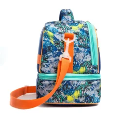 Side profile of a blue dinosaur double-decker lunch bag showing its structural depth, vibrant graffiti pattern, and an orange adjustable strap. High-density fabric bag by a Backpack OEM Supplier.