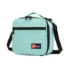 Slanted view of a mint green textured lunch bag with a front zipper pocket and a red logo patch. Functional commuter cooler by a Backpack Supplier.