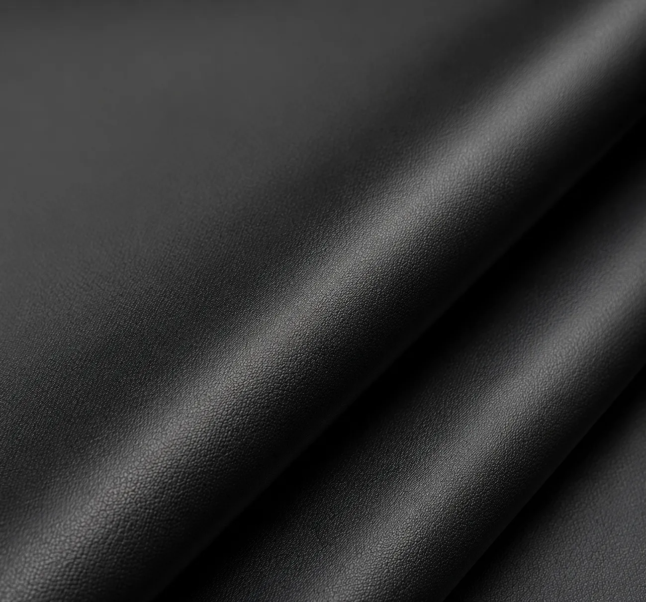 Close-up macro shot of a smooth, fine-grained black synthetic leather or waterproof fabric, showing a sleek and refined texture. Premium durable material for custom backpacks by a professional Backpack Manufacturer.
